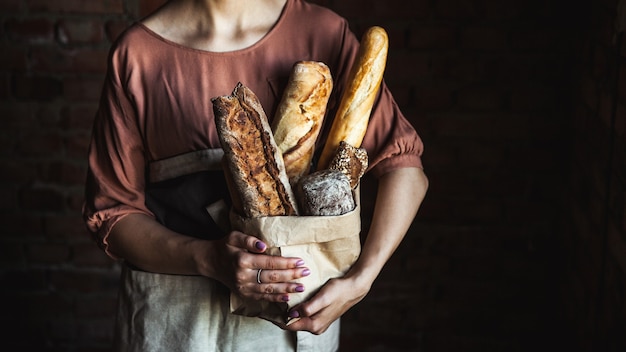 Baguettes francesas en manos femeninas sobre un fondo negro. horneado casero