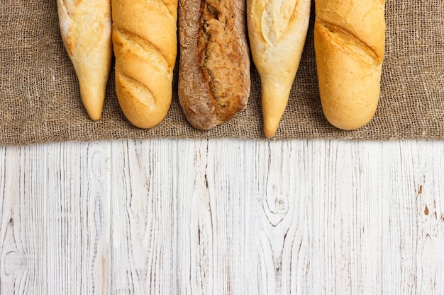 Baguettes francesas recientemente cocidas en la tabla de madera blanca. Vista superior, copia espacio