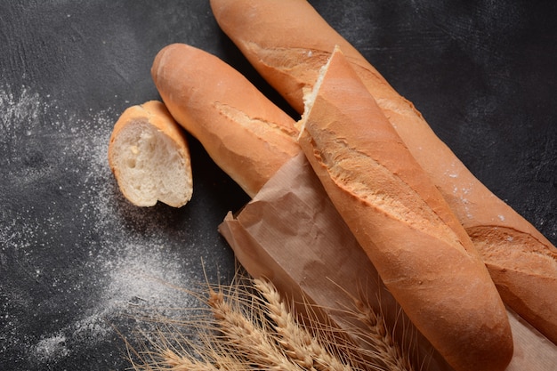 Baguettes de pan fresco francés sobre un fondo oscuro y trigo