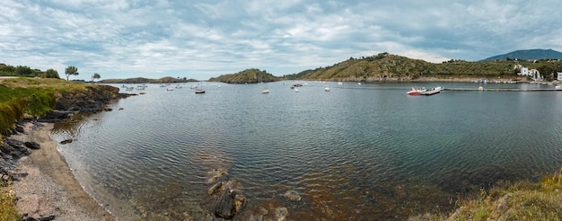 Bahía Cala de Portlligat vista de verano con barcos en el agua (Cadaqués, Girona, España). Las personas y los signos son irreconocibles.