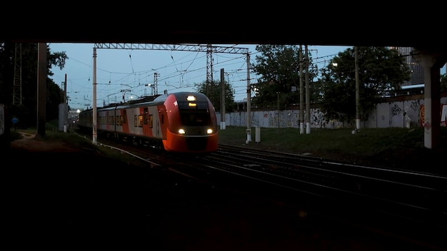 Bahnhof mit einem Zug, der am späten Abend unter der Straßenbrücke fährt