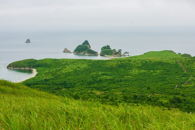 Baía do mar do topo de uma colina de uma costa montanhosa com uma ilha, paisagem de verão e vista do mar em tempo nublado.