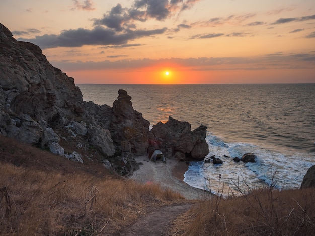 Baía selvagem do mar com uma tenda verde na manhã ao nascer do sol