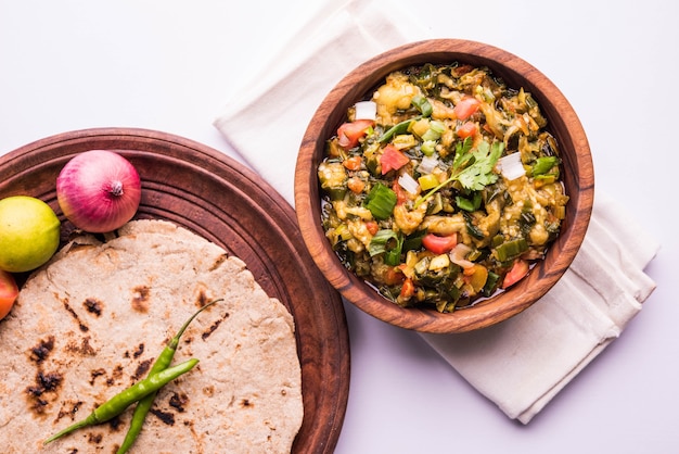 Baigan /Baingan Bharta - Gebratene Auberginenpüree mit Gewürzen und Gemüse gekocht. Serviert mit Fladenbrot aus Jowar-Mehl, bekannt als Bhakar/Bhakri. serviert auf buntem oder hölzernem Hintergrund