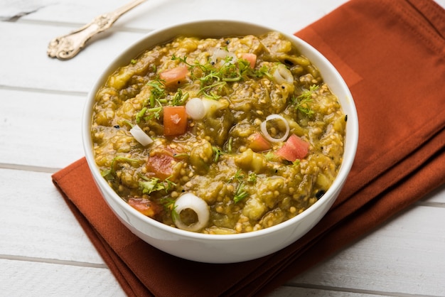 Baigan Bharta en hindi o Vangyache Bharit en marathi es un curry o fritura de berenjena asada y triturada, el menú favorito de Maharashtrian, que se sirve en un tazón o Karhai o sartén. enfoque selectivo