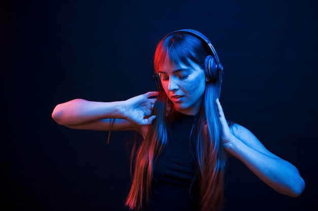 Baila al ritmo. Foto de estudio en estudio oscuro con luz de neón. Retrato, de, niña joven