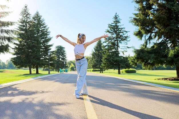 Bailando joven adolescente en la carretera en el parque en un día soleado de verano