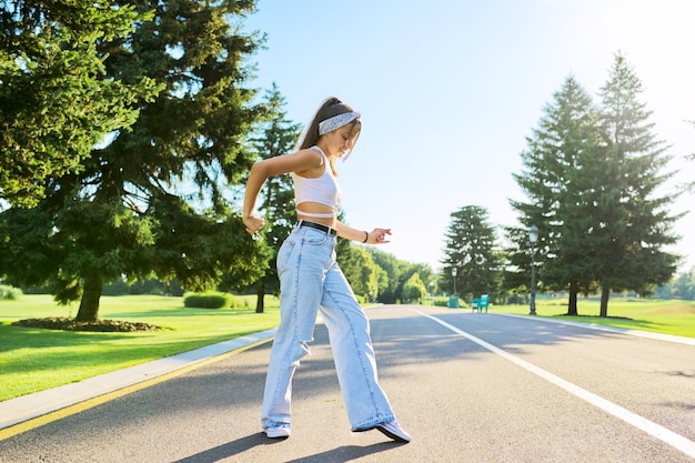 Bailando joven adolescente en la carretera en el parque