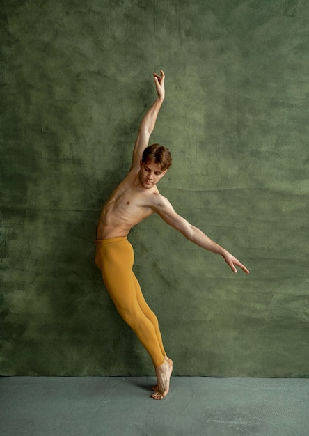 Bailarín de ballet masculino, formación en clase de baile, pared de grunge. Artista con cuerpo musculoso, gracia y elegancia de movimientos.