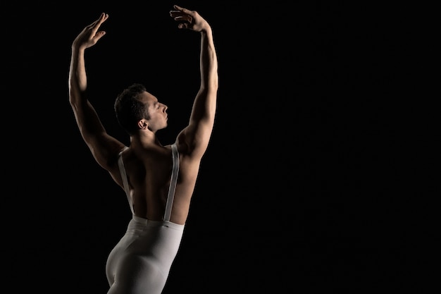 Bailarín de ballet masculino realiza elemento de danza de ballet sobre un fondo negro