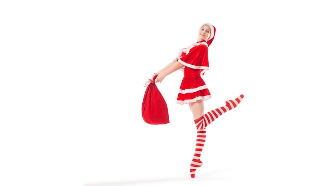 Bailarina bailarina con una bolsa de regalos en sus manos en zapatos de punta en un traje de Papá Noel aislado en un fondo blanco