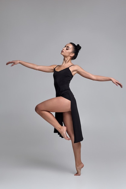 Bailarina de baile con un vestido negro. Rendimiento elegante contemporáneo sobre un fondo gris.