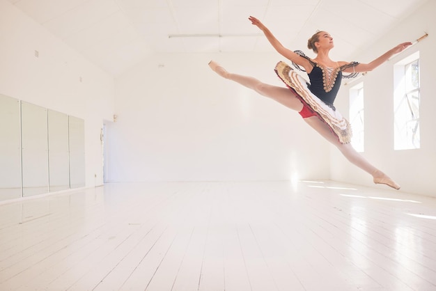 Bailarina de ballet o artista saltando o saltando con un traje de tutú tradicional en un estudio con fondo de espacio de copia Joven artista profesional bailando en pose de globo en el aire