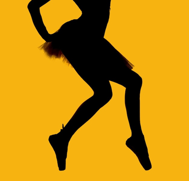 Foto bailarina de ballet de silueta bailando contra un fondo amarillo