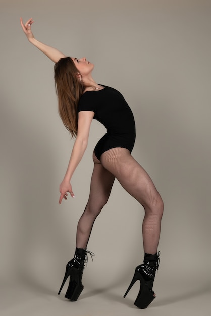 Bailarina de barra hermosa chica flexible en tacones posando en el estudio