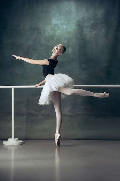 La bailarina clásica posando en la barra de ballet