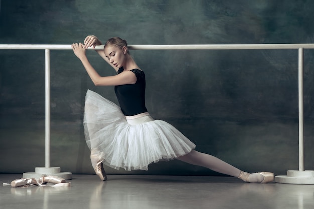 La bailarina clásica posando en la barra de ballet