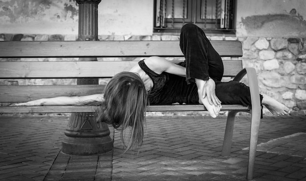 Bailarina contemporánea acostada en un banco en blanco y negro