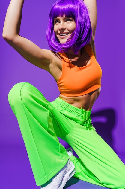 Bailarina despreocupada con ropa deportiva colorida actuando sobre fondo púrpura