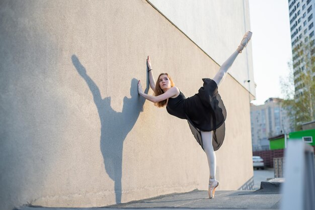 Bailarina em tutu posando em pé perto da parede Linda jovem de vestido preto e ponta dançando do lado de fora Linda bailarina realizando uma dança ao ar livre