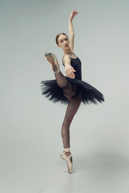 Bailarina em um tutu preto mostra elementos de dança de balé em movimento