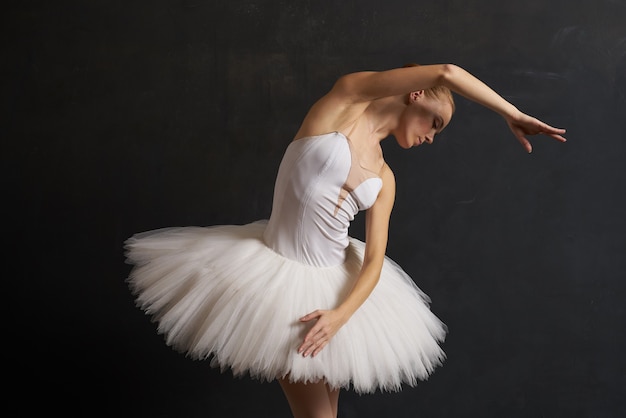 Bailarina em uma silhueta de performance de dança de tutu branco com fundo escuro