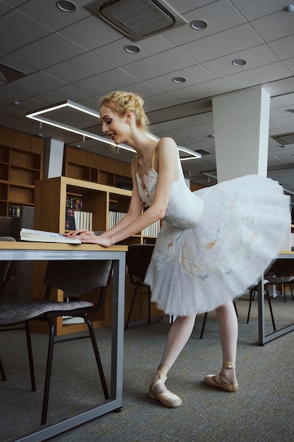 Bailarina encantadora fue a la biblioteca para elegir un nuevo libro durante un descanso mostrando su estiramiento y flexibilidad