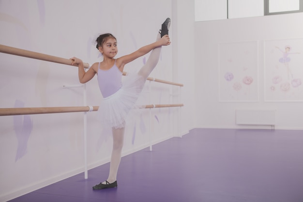 Bailarina encantadora joven haciendo ejercicio en la escuela de baile