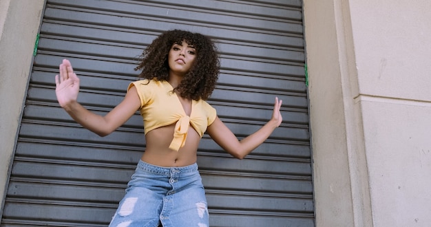 Foto bailarina de estilo moderno con afro en la cabeza bailando en la calle