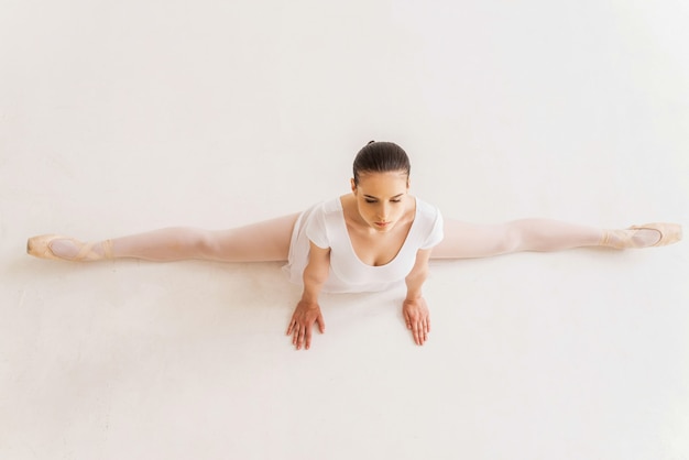 Bailarina fazendo divisões. Vista superior da jovem bailarina em tutu branco fazendo rachaduras