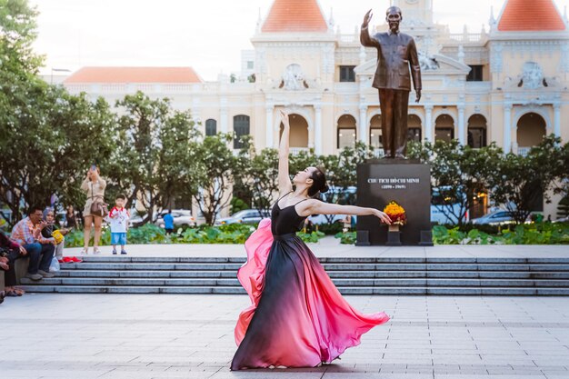 Foto bailarina fazendo espacates no ar na praça da prefeitura da cidade de ho chi minh, no vietnã