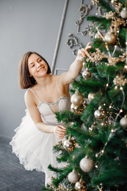 Bailarina feminina em tutu branco decorando a árvore de Natal