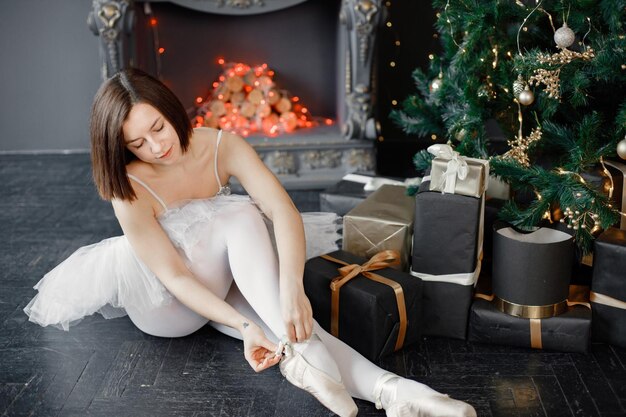 Bailarina feminina em tutu branco e sapatilhas de ponta perto da árvore de Natal