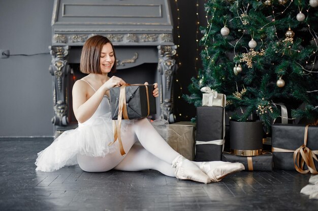 Bailarina feminina em tutu branco e sapatilhas de ponta perto da árvore de Natal