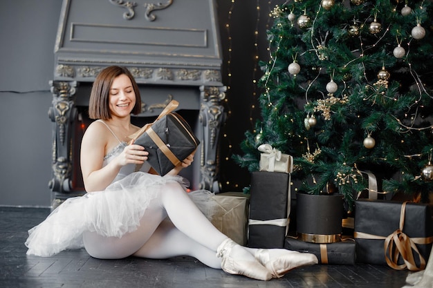 Bailarina feminina em tutu branco e sapatilhas de ponta perto da árvore de Natal