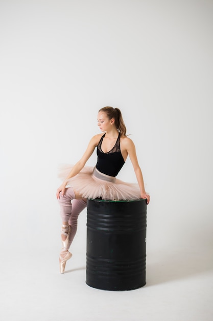 Bailarina en un hermoso traje sentado en un primer plano de barril negro
