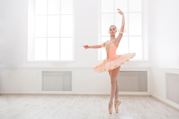Bailarina de joven adolescente haciendo ejercicio en traje de ballet, de pie sobre sus dedos de los pies. Estudiante de ballet practicando danza clásica pas en estudio antes de la actuación