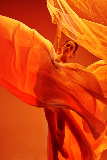 Bailarina. Joven bailarina de ballet femenino agraciado bailando sobre estudio rojo. Belleza del ballet clásico.