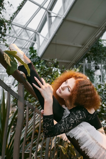 Foto bailarina joven que se extiende en un jardín botánico interior