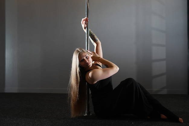 La bailarina en el pilón en el estudio. Chica haciendo ejercicios en un equipamiento deportivo.