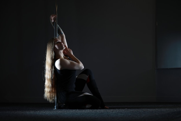 La bailarina en el pilón en el estudio. Chica haciendo ejercicios en un equipamiento deportivo.