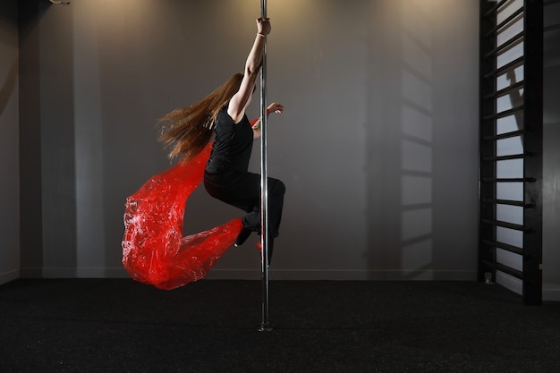 Foto la bailarina en el pilón en el estudio. chica haciendo ejercicios en un equipamiento deportivo.