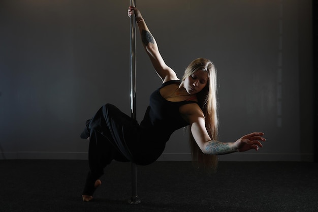 La bailarina en el pilón en el estudio. Chica haciendo ejercicios en un equipamiento deportivo.