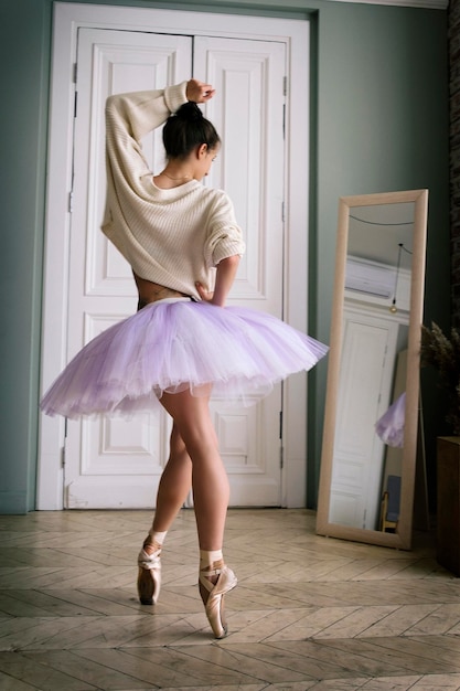 Bailarina posa mostrando as pernas na sala em frente ao espelho em sapatilhas e tutu