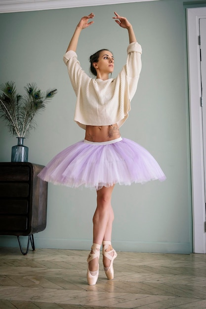 Bailarina posa mostrando sus piernas en la habitación frente al espejo con zapatillas de punta y tutú