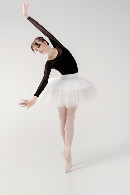 Bailarina con traje negro y tutú posa en movimiento mostrando elementos mientras está de pie en punta