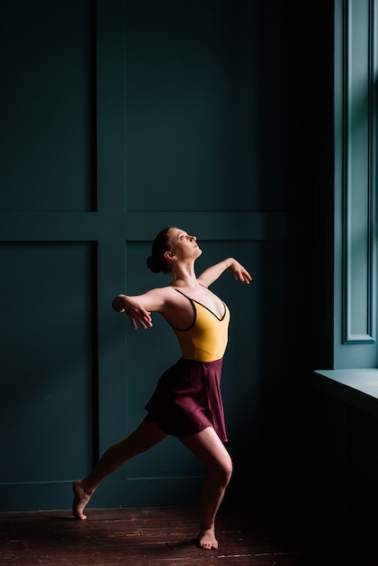 Bailarina en traje oscuro, vestido en estudio interior oscuro.