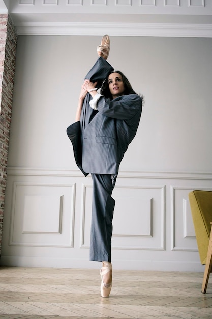 Bailarina con traje de rayas grises y zapatos de punta baila por la habitación