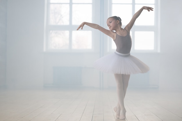 Bailarina vestida de tutu praticando durante a aula em uma escola de balé clássico