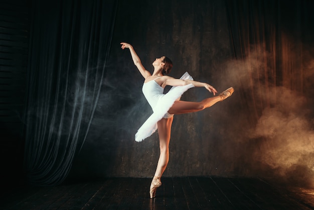 Bailarina en vestido blanco bailando en clase de ballet